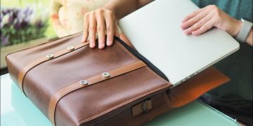 Person packing laptop into laptop bag