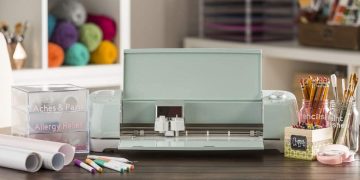 Cricut Explore Air 2 on a desk surrounded by craft supplies.