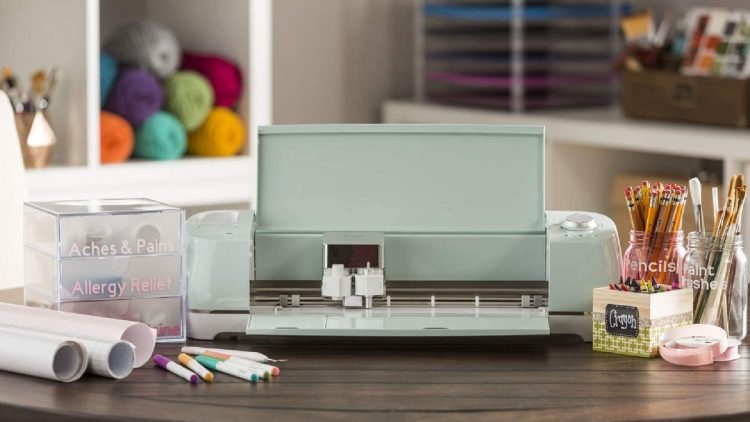 Cricut Explore Air 2 on a desk surrounded by craft supplies.